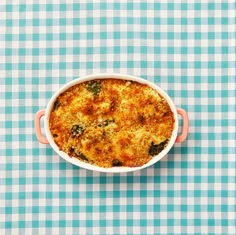 a casserole dish with broccoli in it on a blue and white checkered tablecloth