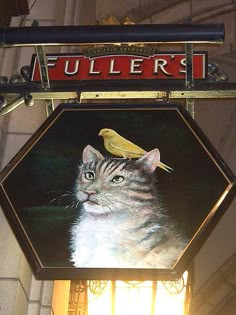 a painting of a cat with a bird on it's head hanging from the side of a building