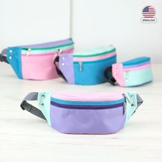 three different colored fanny bags sitting on top of a white table next to each other