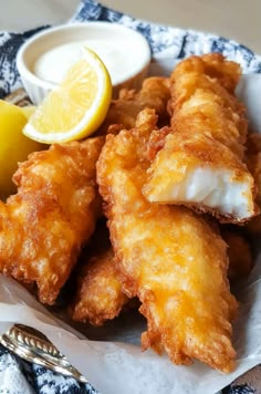 some fried food on a plate with lemon wedges