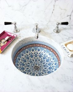 a blue and white sink sitting on top of a counter next to a faucet