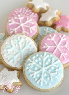 several decorated cookies on a white plate with snowflakes and stars in the middle