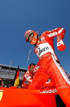 a man in red racing suit standing on top of a race car