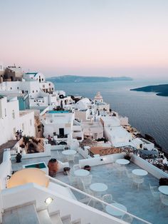 an outdoor dining area overlooking the water and buildings in oia, with tables and chairs