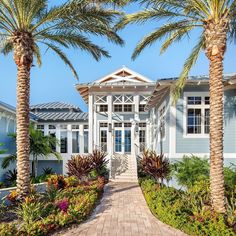 a house with palm trees in front of it and a walkway leading to the front door