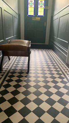 a bench sitting in the middle of a checkered floored hallway with stained glass windows