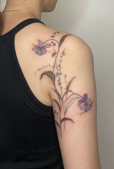 a woman with a tattoo on her shoulder has flowers growing out of the back of her arm