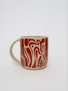 a red and white coffee cup sitting on top of a table