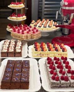 desserts and pastries are displayed on trays in front of a coffee maker