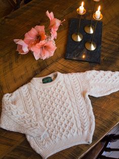 a sweater and candles are sitting on a table next to a candle holder with flowers