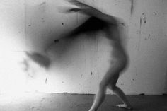 a blurry image of a woman dancing in front of a wall