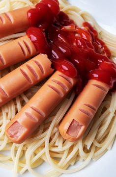 four hotdogs with ketchup and noodles on a plate