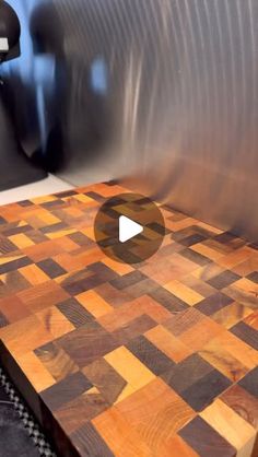 a wooden cutting board sitting on top of a metal table next to a black object