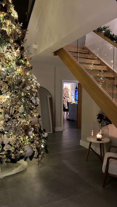 a decorated christmas tree in the middle of a living room with stairs leading up to it