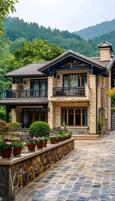 a large stone house with potted plants on the front and side walk leading up to it