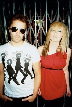 two people standing next to each other in front of a gate