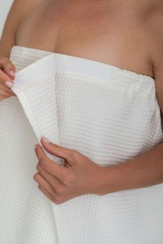 a woman in a white towel is holding her hand on the side of her body