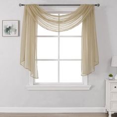 an empty room with a white dresser and window covered in sheer fabric curtains on the windowsill