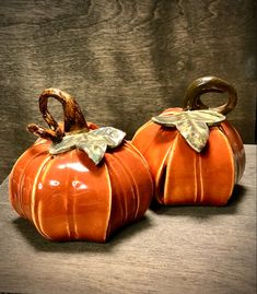 two ceramic pumpkins sitting on top of a wooden table