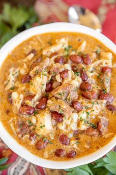 a close up of a bowl of soup with meat and beans in it on a table