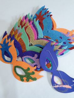 a pile of colorful masks sitting on top of a white table next to a pair of scissors