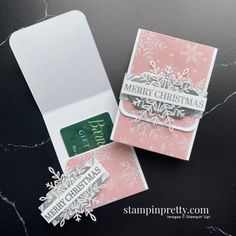 two christmas cards are sitting next to each other on a black surface with white and pink designs