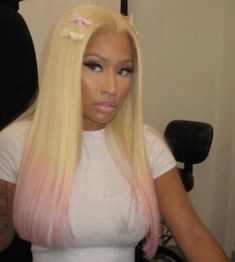 a woman with long blonde hair wearing a white t - shirt and pink ombreved wig