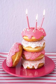 a pink plate topped with donuts covered in frosting and sprinkles