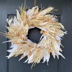 a wreath is hanging on the door with dried flowers and leaves in it's center