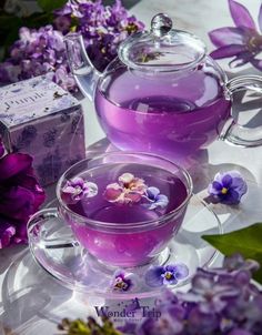 purple flowers and tea are sitting on a table