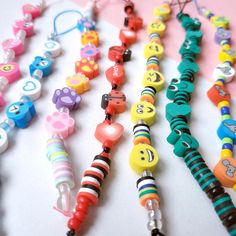 many different colored beads are lined up on a white surface and one bead has an emoticive smiley face