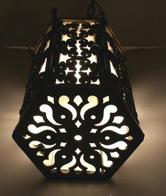 an intricately designed light fixture hanging from the ceiling in a dimly lit room with dim lighting