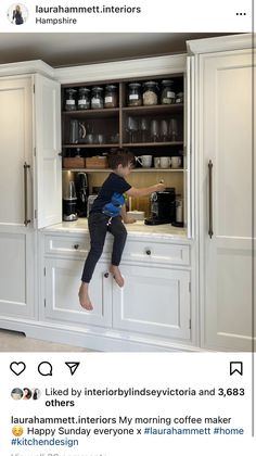 a little boy sitting on top of a kitchen counter next to an open cabinet door