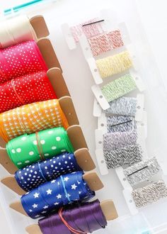 several rolls of colorful ribbon are in a plastic box with white polka dots on them