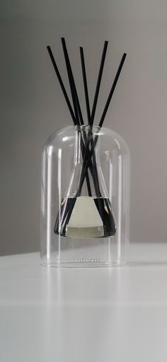 a clear vase with black sticks sticking out of it