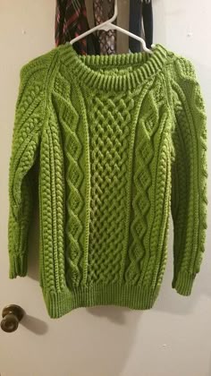 a green sweater hanging on a white wall