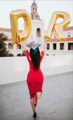 a woman in a red dress holding up two large gold letters