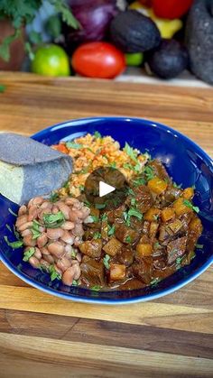 a blue plate topped with beans and rice next to a slice of bread on top of a wooden cutting board