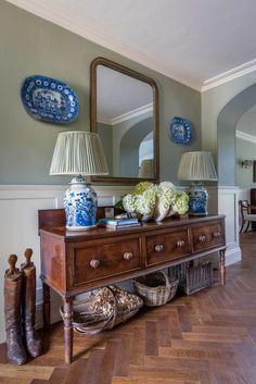 a wooden table topped with blue and white vases sitting next to a large mirror