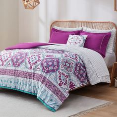 a bed with purple and white comforters in a room