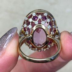 This impressive gemstone ring features a natural 24.10-carat oval-cut kunzite with excellent pink color saturation. Surrounding the center kunzite is a halo of French-cut rubies. The under-gallery is decorated with a lace design and diamonds. This ring is made in 18k yellow gold.
The total approximate ruby weight is 1.20 carats. The total approximate diamond weight is 0.50 carats.
The measurements, including the ruby halo, are 19mm x 25mm.
This ring can be resized to any finger size at no extra Luxury Oval Ruby Ring With Gemstone, Elegant Round Pink Sapphire Gemstones, Luxury Pink Amethyst Gemstone Ring, Luxury Oval Gemstones With Halo Setting, Elegant Pink Kunzite Rings, Exquisite Oval Gemstones With Halo Setting, Pink Oval Multi-stone Ruby Ring, Exquisite Oval Pink Jewelry, Luxury Oval Gemstones