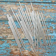 several metal straws sitting on top of a wooden table next to blue paint and wood plank