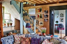 a living room filled with lots of furniture and pictures on the wall next to a stair case