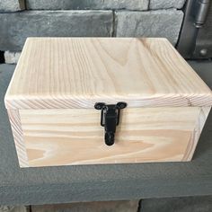 a wooden box sitting on top of a cement floor next to a brick wall with a black handle