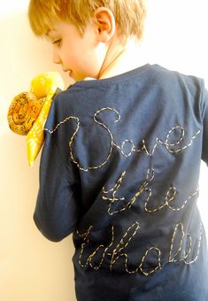 a young boy eating a banana while wearing a shirt that says save the bananas on it