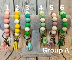 four different colored beads and tassels on a keychain with the word group a