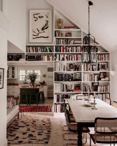 a living room filled with furniture and bookshelves next to a dining room table