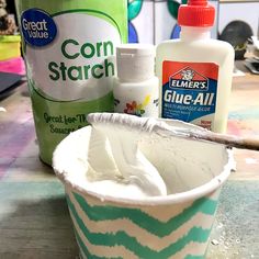 a cup filled with white paint next to some other items