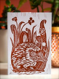 a card with an image of a hedgehog in the middle of flowers and plants