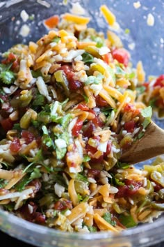 a bowl filled with pasta and veggies on top of a wooden spatula